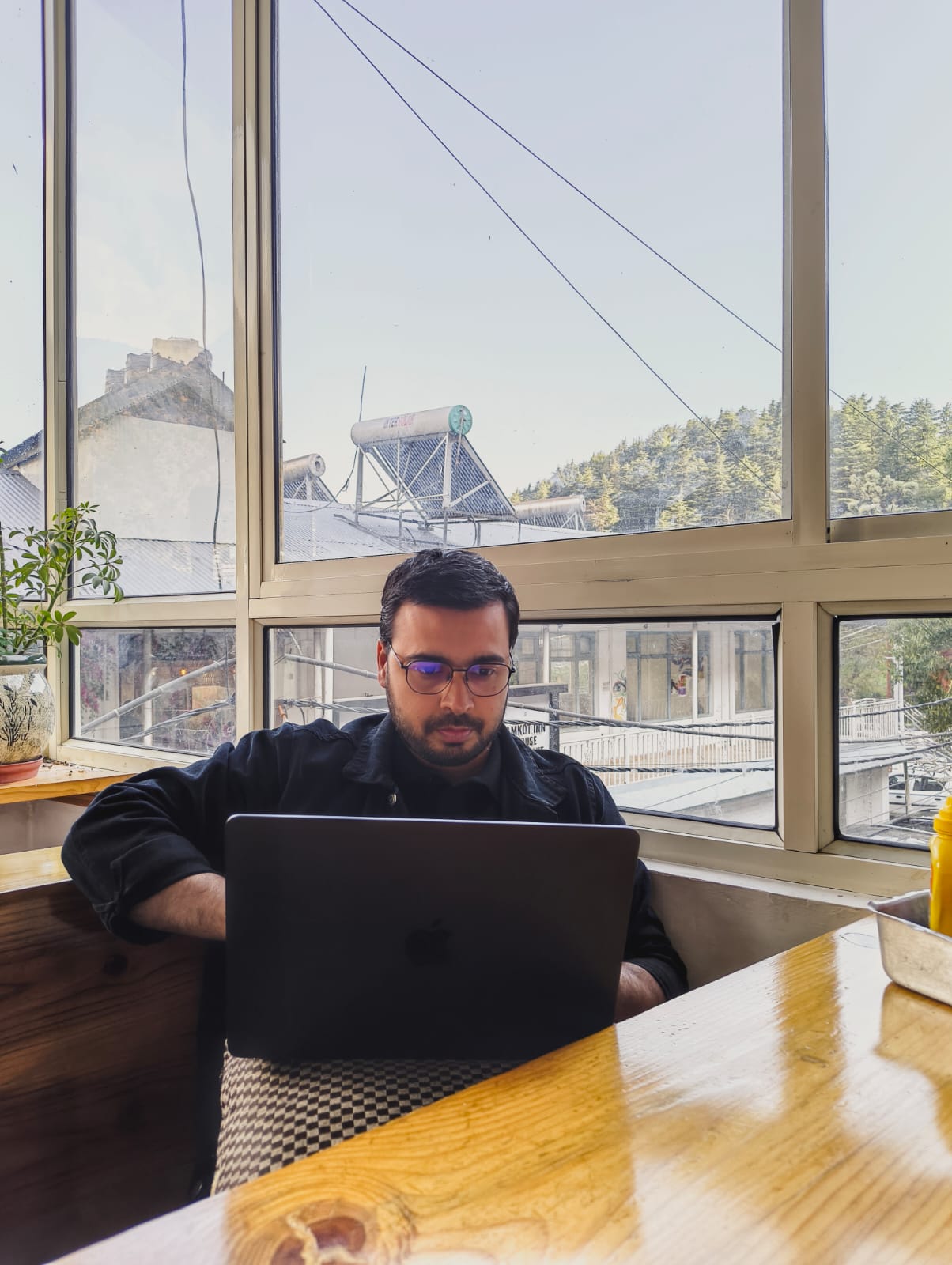 Rahul working on a laptop near a mountain window